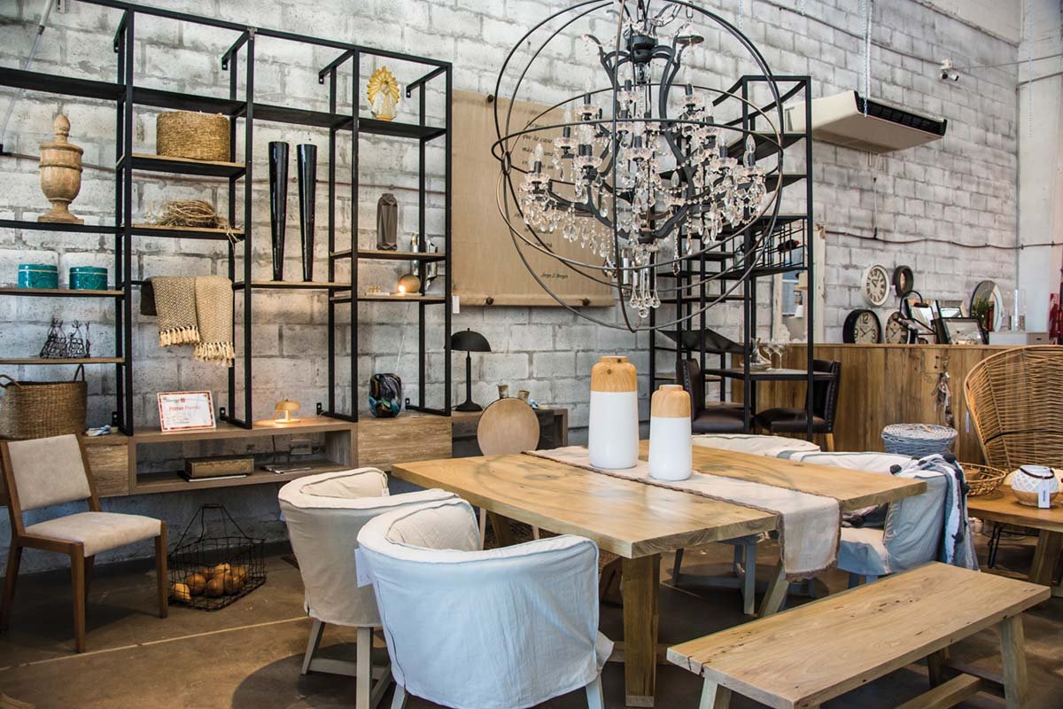 MINI COMEDOR: madera nativa de marcada veta en la mesa cuadrada y los bancos de este rincón. Detrás, biblioteca de hierro negro con bajo en madera y sin patas, acompañada por una bodega, semicurva, en el mismo estilo, y barra informal en madera nativa